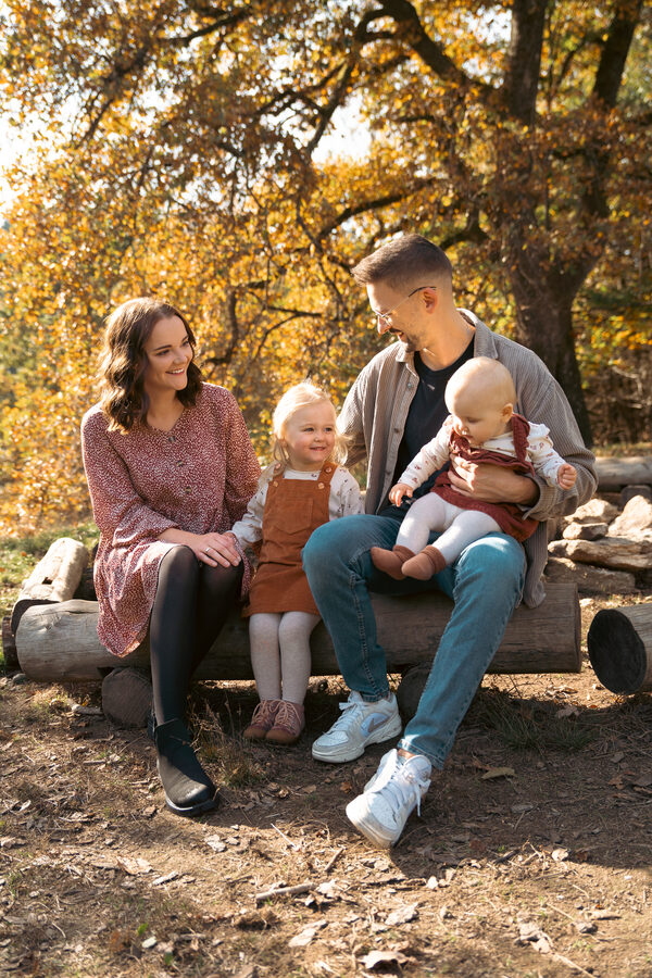 Familie auf einem Baumstamm im Herbstwald